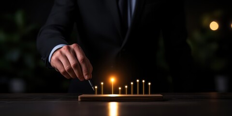 A business person lighting a candle representing growth and inspiration in a dark setting.