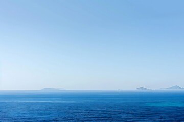 Obraz premium A serene seascape unfolds. Calm blue waters stretch to the horizon, where small islands rest under a clear, bright blue sky. Peaceful and tranquil.