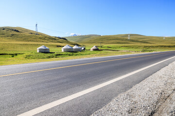 Countryside asphalt road and green meadow with mountain nature landscape in Xinjiang, China. Outdoor road background.