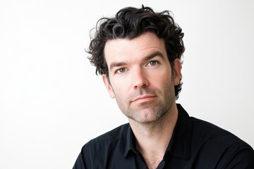 Obraz premium Confident Man with Curly Hair Posing Against a Neutral Background