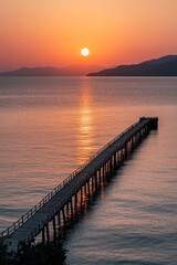 Obraz premium Sunset, a long wooden bridge stretching out into the sea