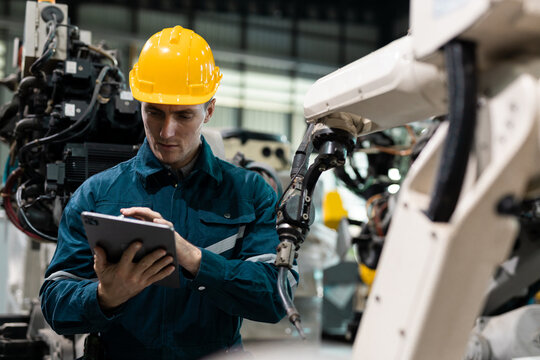 Robotic engineer automatic mechanic checking quality system of automation robot arms machine in factory. Service programming machinery welding robots in production at factory industry.