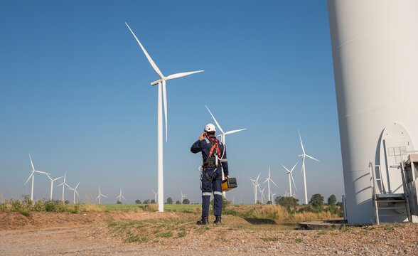 Engineer wearing uniform inspection and survey work in wind turbine farms rotation to generate electricity energy. Maintenance engineer working in wind turbine farm.