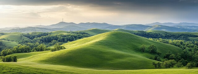 Stunning panoramic view of lush green hills under a dramatic sky with distant mountains and trees