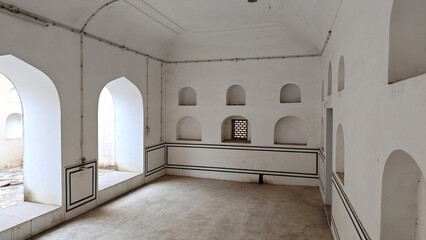 A serene room featuring arched windows, minimalist wall niches, and subtle detailing, showcasing a blend of simplicity and heritage.
