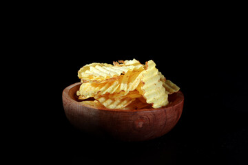 potato chips on a wooden plate with a black background