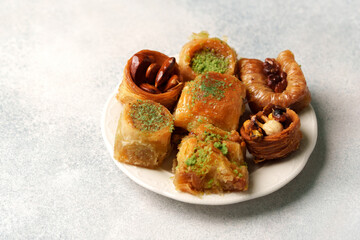 Delicious assortment of traditional pastries served on a white plate with nuts and syrup in a cozy setting