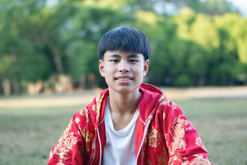 Asian chinese boy in red clothes, sitting and smiling happily, happiness of people concepts.