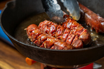 Sizzling smoked sausage sears on a cast iron skillet, releasing its rich aroma as the edges crisp