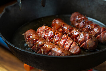 Sizzling smoked sausage sears on a cast iron skillet, releasing its rich aroma as the edges crisp