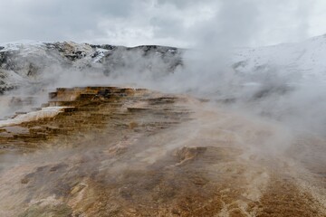 Steam rises from terraced hot springs in Yellowstone National Park. A landscape of geothermal...