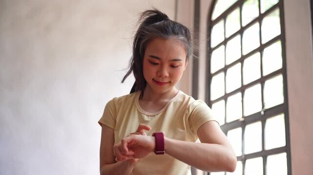 Asian woman using smartwatch check heart rate after exercise at gym