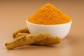 Turmeric (Curcuma longa Linn) powder in a ceramic white bowl with turmeric roots