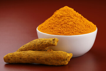 Turmeric (Curcuma longa Linn) powder in a ceramic white bowl with turmeric roots