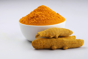 Turmeric (Curcuma longa Linn) powder in a ceramic white bowl with turmeric roots