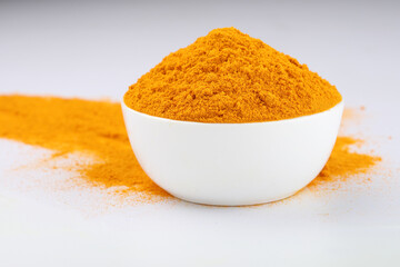 Turmeric (Curcuma longa Linn) powder in a ceramic white bowl with turmeric roots