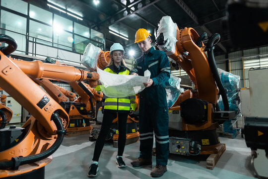 Robotic engineer team automatic holding blueprint checking Plan system of automation robot arms machine in factory. Service programming machinery welding robots in production at factory industry.