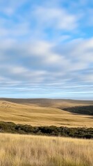 Fototapeta premium A serene landscape featuring rolling hills and a blue sky with scattered clouds.
