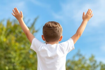 Young boy with raised arms outdoors facing blue sky