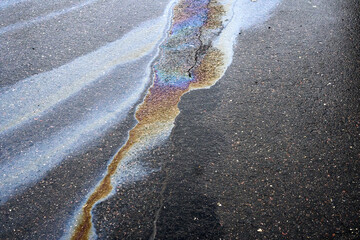 A rainbow colored oil spill creates a striking rainbow effect on a damaged asphalt surface