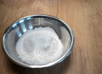 Sifted  white  sugar in a stainless steel bowl prepared as an ingredient for baking cakes, gingerbread, or for preparing sweet dishes.
