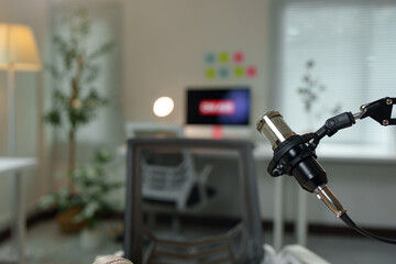 Condenser microphone capturing high-quality sound in a modern home studio, perfect for podcasting, voiceovers, and music production, with a blurred workspace background