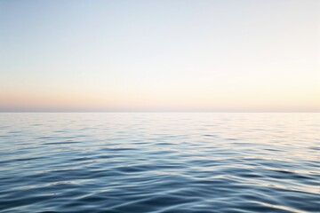 Obraz premium Tranquil ocean surface under soft sunrise sky creating a serene and peaceful atmosphere.