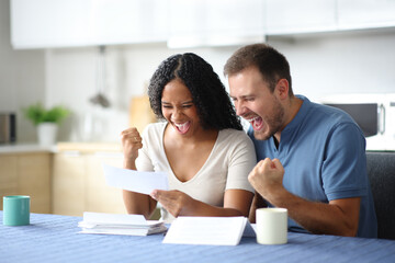 Excited interracial couple checking invoice celebrating