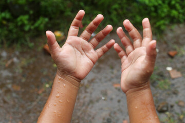 the little child's hands are wet from the splashes of rain that fell