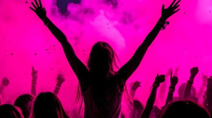 Woman with arms raised at vibrant concert.