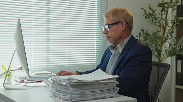 Office worker checking paperwork and using computer, managing projects and organizing files with efficiency and expertise in a corporate setting