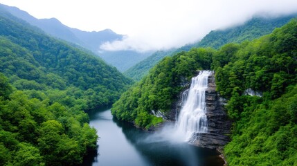 Fototapeta premium Serene waterfall cascading into a tranquil river amidst lush mountains.