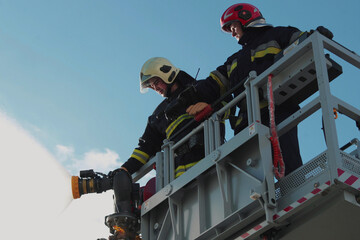 Firefighters stand in a special lifting cradle and put out a fire with a fire hose. The footage shows hard work in extreme conditions. Ideal for themes about rescue operations.