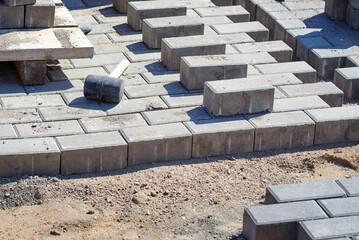 Brick laying and paving slab installation using rubber hammer and tools, outdoor construction work for pathways and patios. Concrete paving slabs laid with rubber hammer