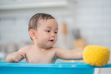 Asian Little child in a bath tub. Washing in bath. Kid with soap suds on hair taking bath. Closeup...