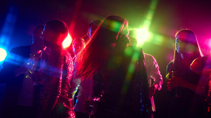 Joyful toasts and carefree dancing bring night alive, with neon lights and rhythmic music amplifying holidays celebration. Concept of party, youth, carefree, celebration. ad