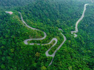 Aerial drone view of winding mountain road surrounded with greenery rainforest at Wang Kelian, Perlis, Malaysia.