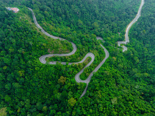 Aerial drone view of winding mountain road surrounded with greenery rainforest at Wang Kelian, Perlis, Malaysia.