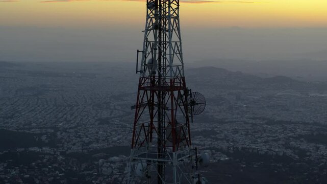 Telecommunications Cell Tower on top of mountain with city in the background at dusk