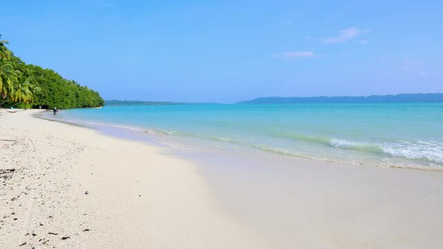 Pristine Coastal Scene with Rolling Waves on White Sand Beach and bright blue sky video is taken at Radhanagar Beach at Havelock Island in the Andaman and Nicobar Islands.