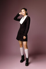 Fototapeta premium Fashionable Asian business woman have good figure and clear fresh skin in black trendy dress pose on isolated pink background. Body and skin care, health, spa, cosmetics.