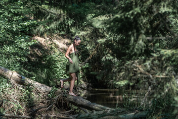 Naklejka premium Beautiful young girl posing in a fast forest river in summer.