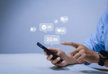 Close-up of man's hand using smartphone to play social media with emoticons or notifications popup.