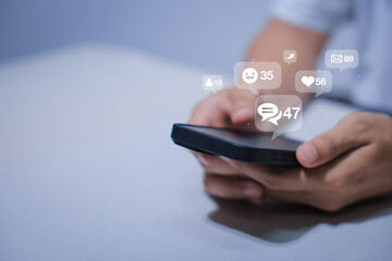 Close-up of man's hand using smartphone to play social media with emoticons or notifications popup.