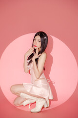 Trendy Beautiful confident Asian woman in pink sexy dress with perfect slim body clean fresh skin in lighting studio. Fashionable female model.