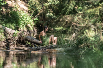 Beautiful young girl posing in a fast forest river in summer.