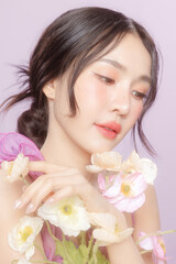 Young Asian beauty woman model pull back hair with natural makeup on face and perfect clean skin with flower on violet background. Facial treatment, Cosmetology, Spa, Aesthetic, plastic surgery.