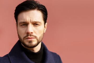 Fototapeta premium Calm young man with a beard wearing black clothes posing outdoors, looking at camera