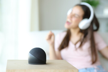 Woman singing listening music with smart speaker in foreground