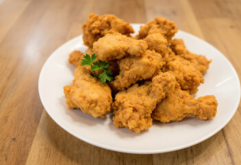 Fried chicken pieces on a white plate on a wooden surface